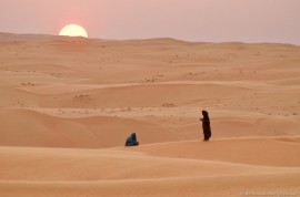 Beduin women praying at sunset in the desert in Wahiba Sands, Oman, 2011